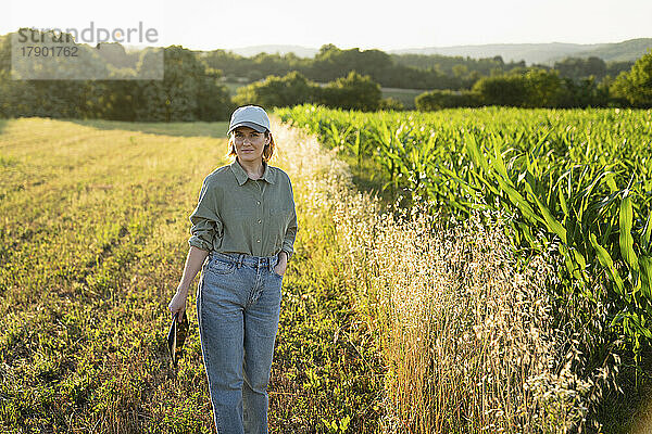 Frau steht auf dem Feld und hält ein digitales Tablet in der Hand