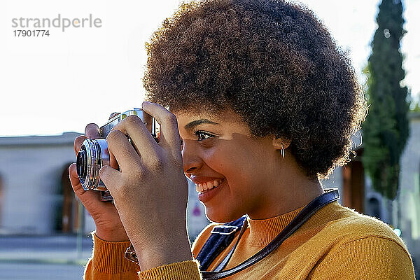 Lächelnde junge Frau  die mit der Kamera fotografiert