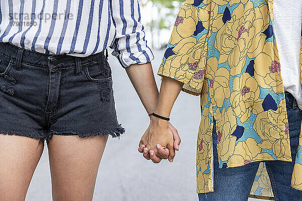 Young women holding hands at park