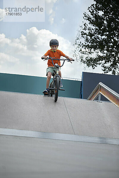 Junge fährt BMX-Fahrrad im Skateboardpark vor dem Himmel