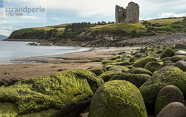 Irland  Kilmurry  am Strand liegende Felsbrocken mit alter Ruine im Hintergrund