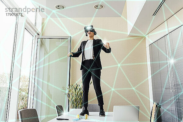 Geschäftsfrau trägt Virtual-Reality-Simulator und steht auf einem Tisch im Büro