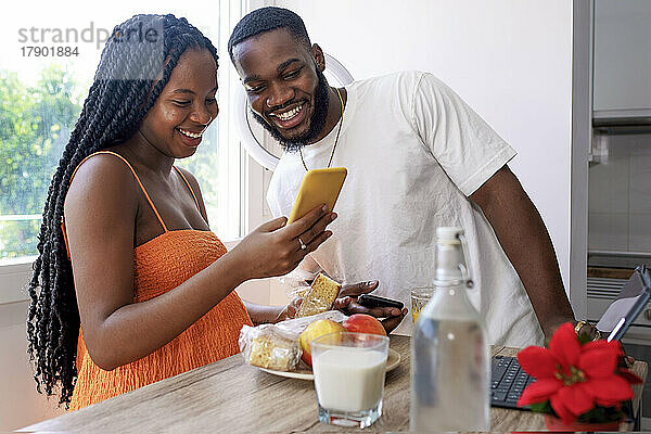 Glückliches Paar  das zu Hause sein Smartphone teilt
