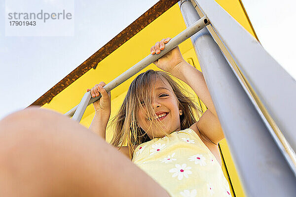 Happy girl holding railing sitting on lifeguard hut