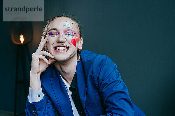 Lächelnder Mann mit Make-up vor der Wand