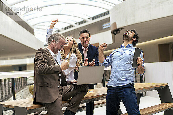 Glückliche Geschäftskollegen feiern gute Nachrichten im Bürokorridor