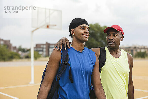 Reifer Mann spricht mit Sohn beim Spaziergang auf dem Basketballplatz