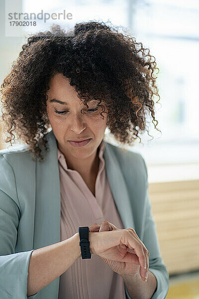 Reife Geschäftsfrau überprüft die Zeit auf einer Smartwatch