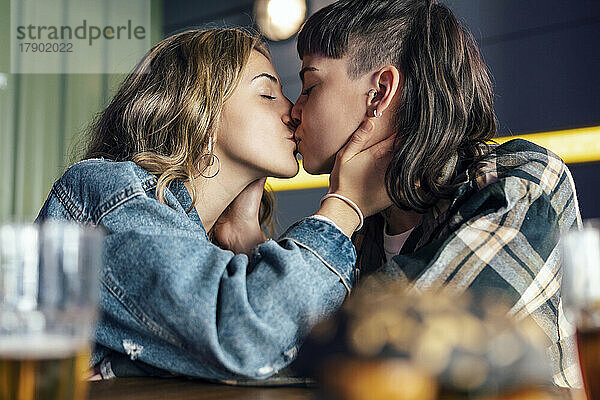 Young lesbian couple kissing each other at restaurant