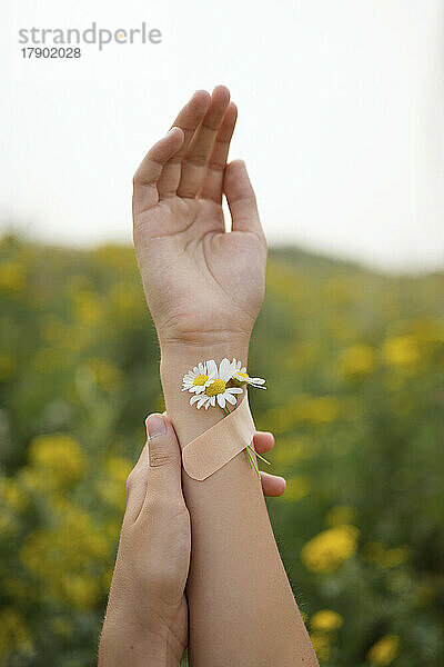 Mädchen mit Blumen  die mit einem Pflaster an der Hand befestigt sind