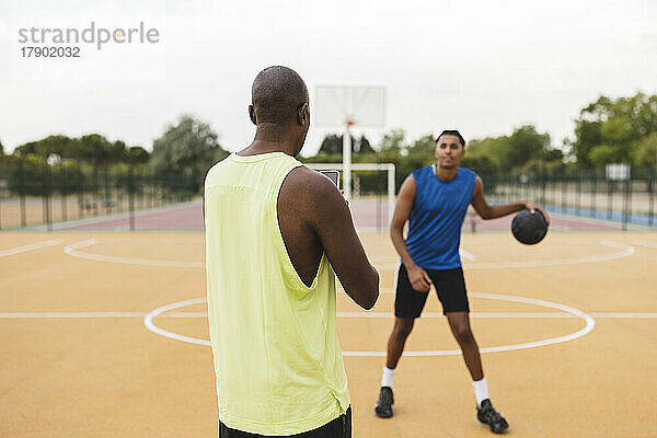 Vater filmt Sohn beim Dribbeln des Balls auf Basketballplatz