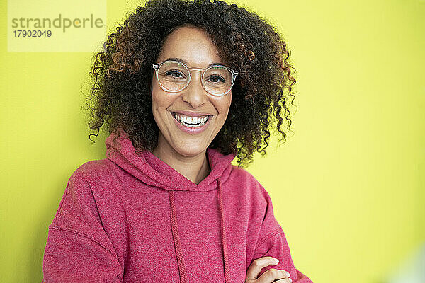 Happy woman with eyeglasses in front of green wall