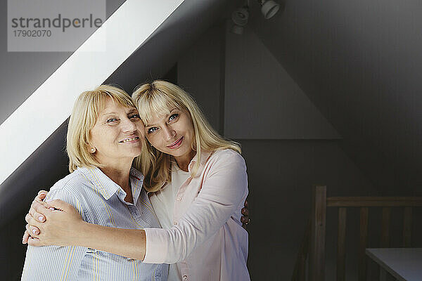 Lächelnde Frau umarmt Mutter  die zu Hause steht