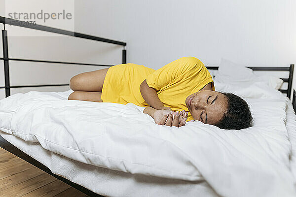 Exhausted woman in yellow t-shirt sleeping on bed at home