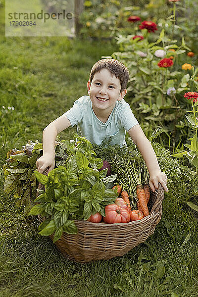 Glücklicher Junge mit Gemüsekorb im Garten
