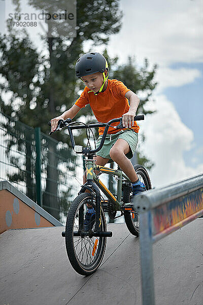 Junge übt mit BMX-Fahrrad auf Sportrampe
