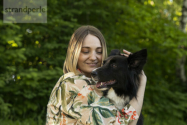 Glückliche junge Frau mit süßem Hund im Park