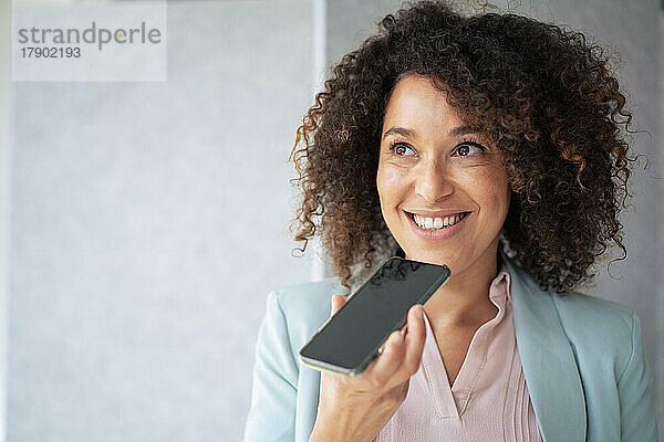 Lächelnde Geschäftsfrau  die Voicemail über ihr Smartphone sendet