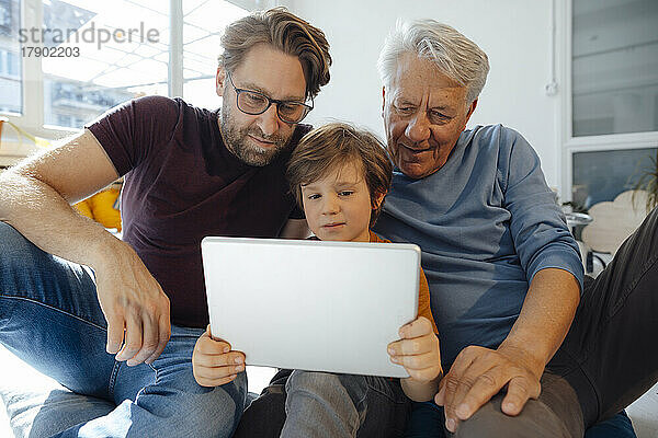 Junge schaut sich zu Hause mit Vater und Großvater auf dem Tablet-PC einen Film an
