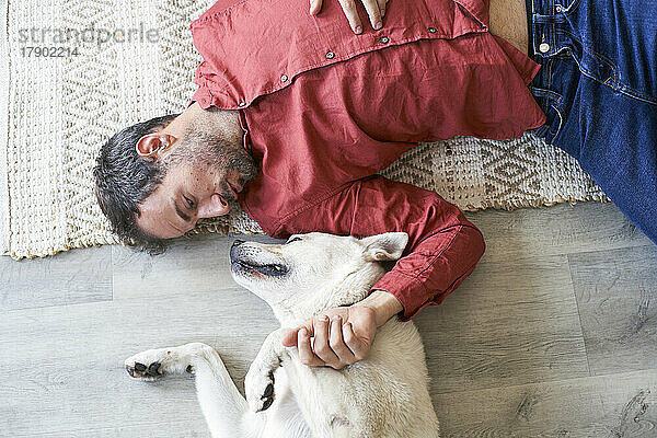 Mann liegt mit Hund zu Hause auf dem Boden