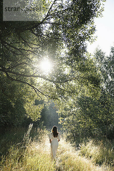 Frau im weißen Kleid geht im Wald spazieren