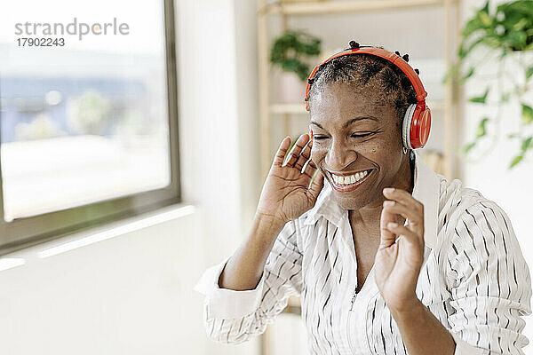 Lächelnde Frau  die zu Hause Musik über kabellose Kopfhörer hört