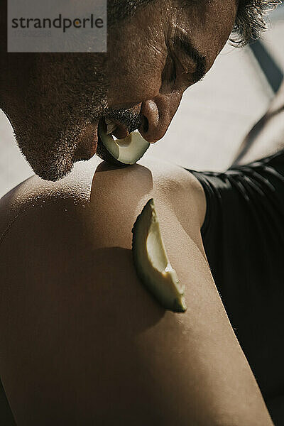 Romantischer Mann isst Avocadoscheibe aus der Hüfte einer Frau