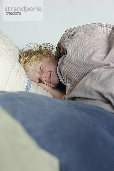 Lächelndes Mädchen mit geschlossenen Augen entspannt im Bett