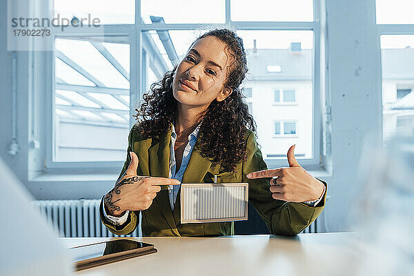 Lächelnde Geschäftsfrau zeigt im Büro auf Solarpanel