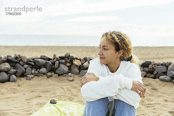 Smiling young woman enjoying weekend sitting at beach