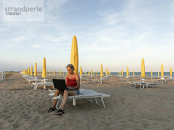 Ältere Geschäftsfrau benutzt Laptop am Strand