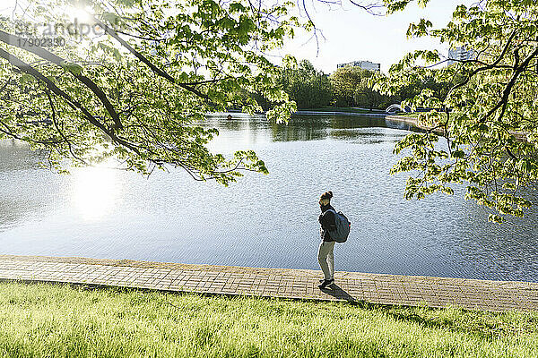 Man with backpack walking by lake on footpath