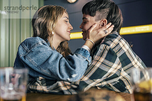 Liebevolles junges lesbisches Paar sitzt am Tisch im Restaurant