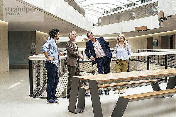 Lächelnde Geschäftskollegen blicken zum Bürokorridor