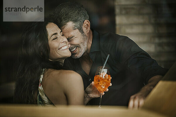 Mature romantic couple with drink laughing in restaurant