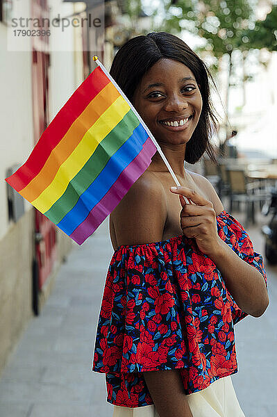 Glückliche junge Frau mit Regenbogenfahne