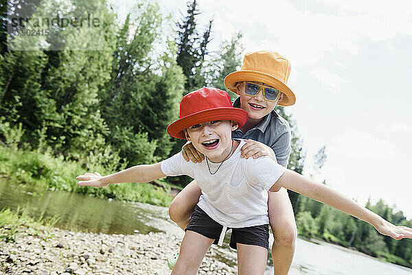 Glückliche Brüder mit Hüten am Flussufer