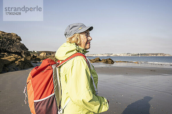 Lächelnde ältere Frau am Strand an einem sonnigen Tag