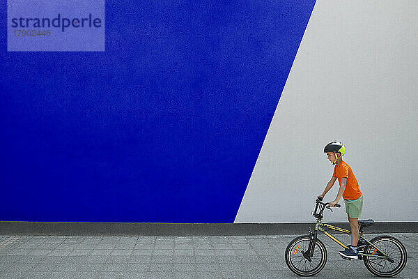 Junge beim BMX-Radfahren an zweifarbiger Wand