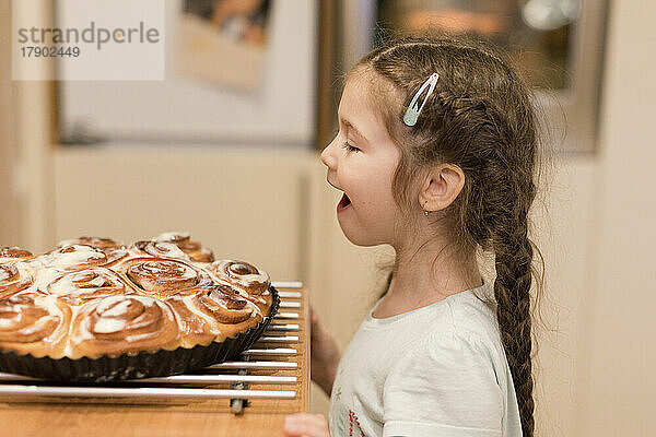 Little girl admiring freshly baked cinnamon buns