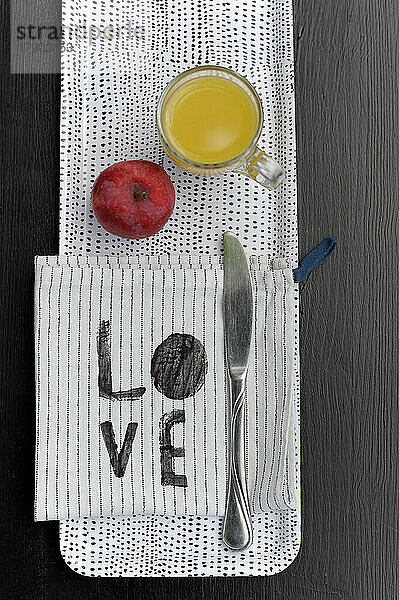 Spotted tray with apple  glass of orange juice  dish towel and table knife