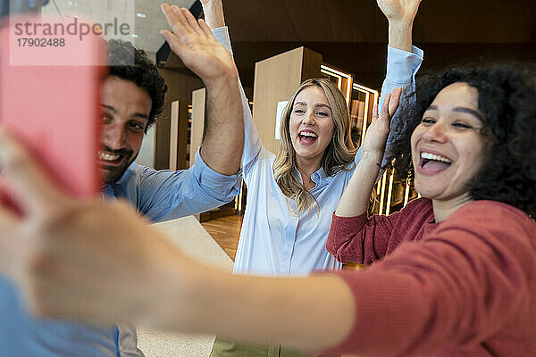 Fröhliche Kollegen machen Selfie mit dem Smartphone in der Bibliothek