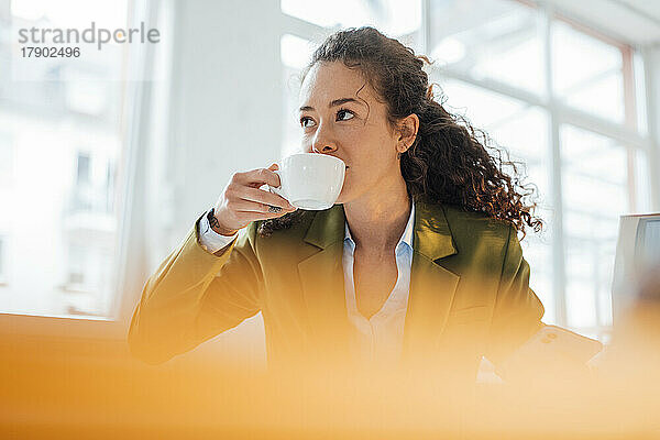 Junge Geschäftsfrau mit lockigem Haar  die Kaffee trinkt