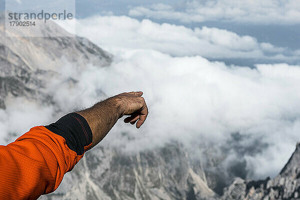 Hand of mountaineer gesturing from top of the mountain