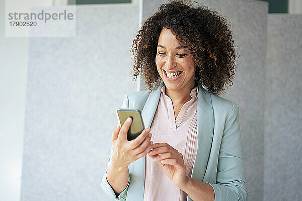 Cheerful businesswoman using mobile phone at office
