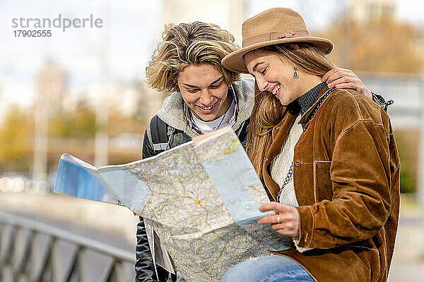 Glücklicher Mann und Frau  die im Urlaub Karte lesen