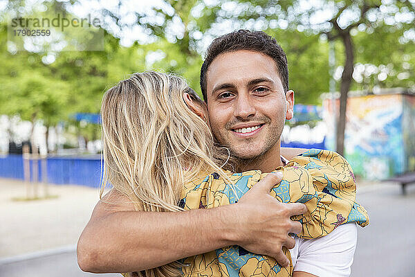 Lächelnder Mann umarmt Freundin im Park