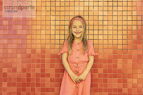Smiling girl with standing in front of wall