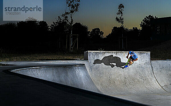 Junger Mann fährt Tretroller im Skateboardpark