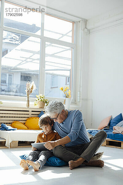 Enkel und Großvater nutzen Tablet-PC im Wohnzimmer